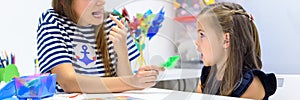 Children speech therapy concept. Preschooler practicing correct pronunciation with a female speech therapist. Web banner.