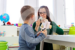 Children speech therapy concept. Preschooler practicing correct pronunciation with a female speech therapist.