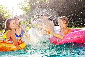 Children splash in swim pool playing together