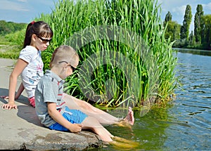 Children splash their feet in the water of the lake.