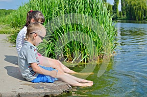 Children splash their feet in the water of the lake.