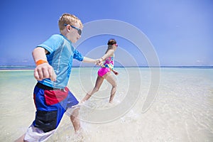 Children splashing in the ocean on a tropical beach vacation