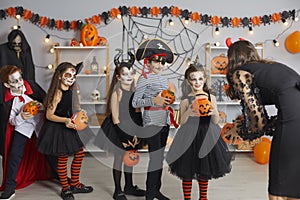 Children in spooky costumes trick or treating and getting candy at Halloween party