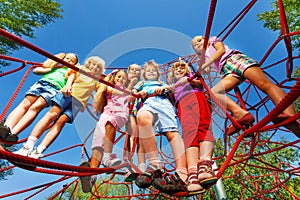 Children stand close on ropes of playground net