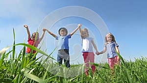 Children stand in a field holding hands, holding them high in the air and laughing. Children stand in a field in the