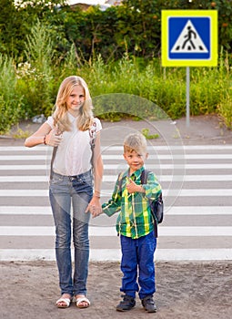 Children stand near a pedestrian crossing and showing thumbs up