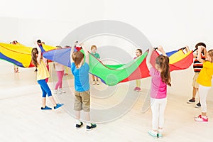 Children standing in circle and waving parachute