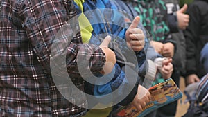 Children standing at park raise their thumbs up