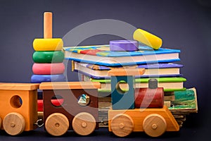 Children storybooks, wood toys, puzzle color train wagons stand on dark blue background