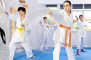 Children students repeat position and perform sequence of punches and painful techniques kata