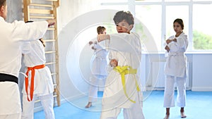 Children students repeat position and perform sequence of punches and painful techniques kata