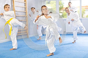 Children students repeat position and perform sequence of punches and painful techniques kata