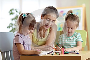 Children students with teacher drawing in art school class. Mother and kids at home. Children indulge.