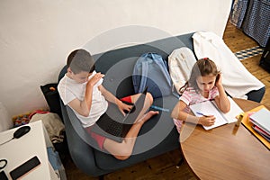 Children studying at home using laptop and notebook
