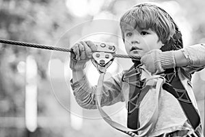 Children summer activities. Portrait of a beautiful kid on a rope park among trees. Every childhood matters. Active