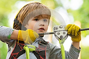 Children summer activities. Portrait of a beautiful kid on a rope park among trees. Every childhood matters. Active