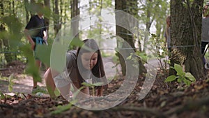 Children in a summer camp hike crawls on the ground. Training of passing obstacles by crawling on the ground. A girl