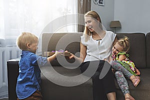 children surprising mother with gift box for birthday or mothers day