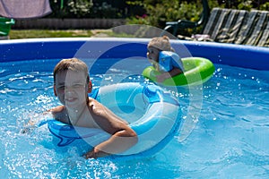 Children swim in the blue pool on a hot summer sunny day. Children have fun swimming in the cool water of the pool. In
