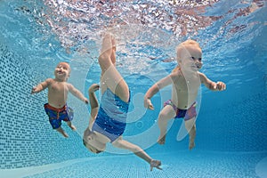 Children swim and dive underwater with fun in swimming pool