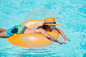 Children swim with floating ring in swimming pool. Kids summer vacation. Happy little boy with inflatable ring in