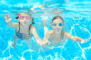 Children swim in pool under water, happy active girls in goggles have fun, kids sport