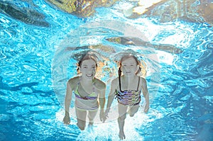 Children swim in pool underwater, girls have fun in water