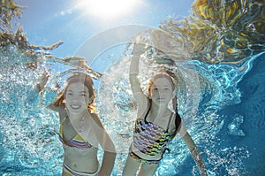 Children swim in pool underwater, girls have fun in water