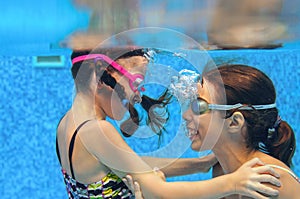 Children swim in pool underwater, happy active girls in goggles have fun under water, kids sport