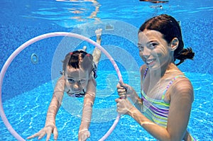 Children swim in pool underwater, happy active girls have fun under water