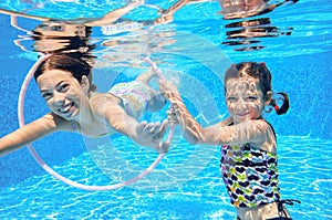 Children swim in pool underwater, happy active girls have fun under water, kids sport