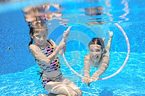 Children swim in pool underwater, happy active girls have fun under water, kids sport