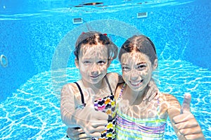 Children swim in pool underwater, happy active girls have fun under water, kids sport