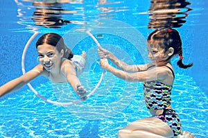 Children swim in pool underwater, happy active girls have fun under water