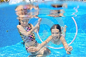 Children swim in pool underwater, happy active girls have fun under water, kids sport