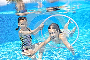 Children swim in pool underwater, happy active girls have fun under water