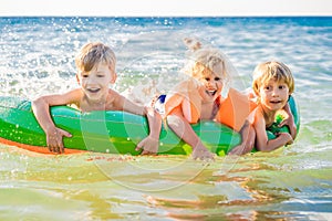Children swim in the sea on an inflatable mattress and have fun