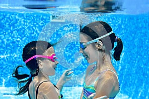 Children swim in swimming pool underwater, happy active girls have fun under water, kids fitness and sport