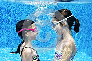Children swim in swimming pool underwater, happy active girls have fun under water, kids fitness and sport