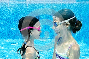 Children swim in swimming pool underwater, happy active girls have fun under water, kids fitness and sport