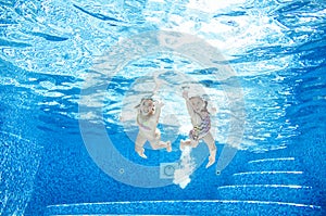 Children swim underwater in swimming pool, happy active girls have fun under water, kids fitness and sport