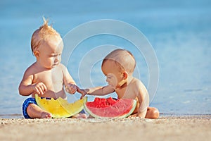 Children after swimming have fun and eat fruits on beach