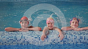 Children in a swimming lesson learn how to move their feet correctly in the pool