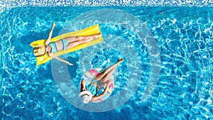 Children in swimming pool aerial drone view fom above, happy kids swim on inflatable ring donut and mattress