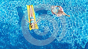 Children in swimming pool aerial drone view fom above, happy kids swim on inflatable ring donut and mattress, girls have fun