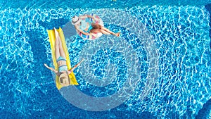 Children in swimming pool aerial drone view fom above, happy kids swim on inflatable ring donut and mattress, girls have fun