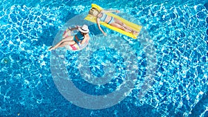 Children in swimming pool aerial drone view fom above, happy kids swim on inflatable ring donut and mattress, girls have fun