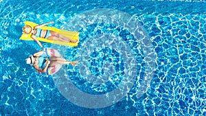 Children in swimming pool aerial drone view fom above, happy kids swim on inflatable ring donut and mattress, girls have fun