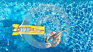 Children in swimming pool aerial drone view fom above, happy kids swim on inflatable ring donut and mattress, girls have fun
