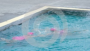 Children in swimming pool having fun during family summer vacation.